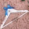 Percha de madera infantil personalizada para bodas en color blanco con nombre grabado Joel, fecha 1 de Agosto de 2026, lazo azul real y frase La boda de mis papis junto a relieve Hijo, de Aura's Personality