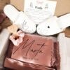 Pack de regalo para prima de la novia Marta con bata de encaje rosa viejo, zapatillas básicas universales blancas y coletero de satén en caja con dedicatoria.