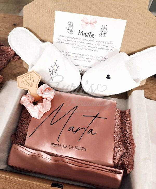 Pack de regalo para prima de la novia Marta con bata de encaje rosa viejo, zapatillas básicas universales blancas y coletero de satén en caja con dedicatoria.