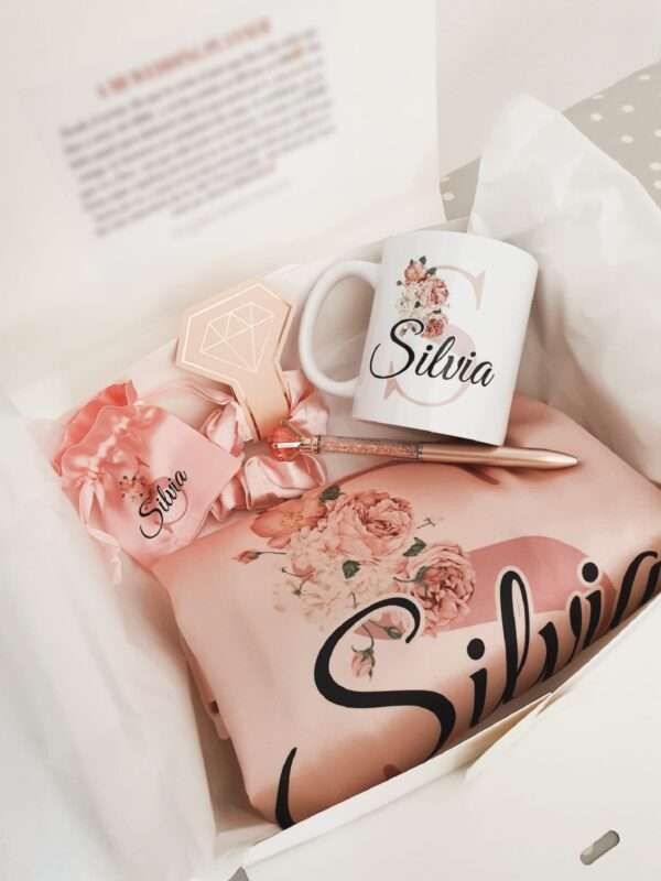 Set Personalizado de Regalo para Boda: Bata Rosa, Taza con Inicial Floral y Accesorios a Conjunto Sorprende a la novia o a tus damas de honor con este exquisito set personalizado de regalo para boda, que combina elegancia y un toque personal. Este set incluye una bata rosa personalizada, una taza a juego con nombre e inicial floral, y accesorios cuidadosamente seleccionados, todo presentado en una elegante caja con dedicatoria. Características del set de boda: Bata Rosa Personalizada: Ideal para la novia o las damas de honor, perfecta para los momentos previos a la boda. Personalización con nombre o iniciales, añadiendo un toque exclusivo a la ocasión. Suave y cómoda, en un delicado tono rosa, perfecta para lucir mientras te preparas para el gran día. Taza Personalizada con Nombre e Inicial Floral: Un recuerdo perfecto para la novia o el equipo de la boda, con un diseño encantador de inicial floral. Personalizada con el nombre, ideal para disfrutar de un café mientras se preparan para la ceremonia. Coletero de Satén a Juego: Fabricado en satén suave, este coletero no solo complementa la bata, sino que también cuida el cabello durante la preparación. Un accesorio a conjunto que añade un toque de estilo a las fotos previas a la boda. Bolígrafo Elegante: Un detalle útil y sofisticado para firmar documentos importantes, como la licencia de matrimonio. Diseño refinado que hace de este bolígrafo un accesorio esencial en cualquier boda. Caja con Dedicatoria Personalizada: Caja de presentación que incluye un mensaje personalizado, expresando gratitud y afecto hacia la novia o las damas de honor. Perfecta como regalo de agradecimiento en la boda, haciendo que cada detalle cuente. Este set personalizado es el regalo de boda perfecto para la novia o las damas de honor, combinando estilo, utilidad y un toque personal. Ideal para recordar los momentos especiales del gran día y agradecer a quienes forman parte de él.