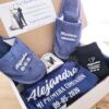 Set de comunión premium para niño en color azul marino con bata personalizada, zapatillas, calcetines y taza en caja de regalo.