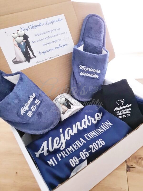 Set de comunión premium para niño en color azul marino con bata personalizada, zapatillas, calcetines y taza en caja de regalo.
