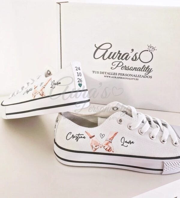 Zapatillas blancas de boda personalizadas con ilustración de manos entrelazadas en acuarela junto a la caja de Aura's Personality.